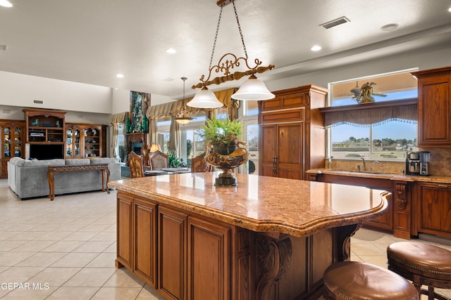 kitchen featuring sink, light stone counters, a center island, hanging light fixtures, and a kitchen breakfast bar