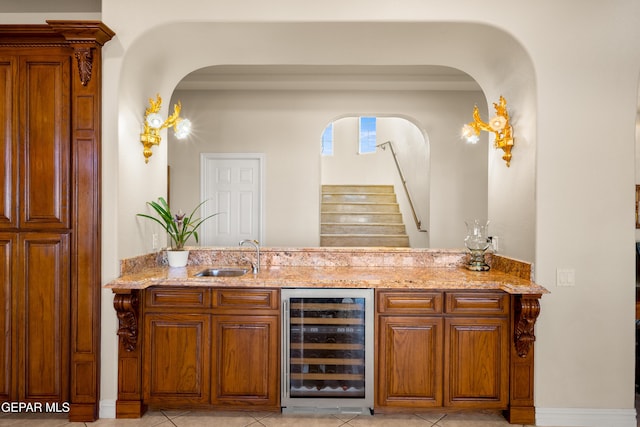 bar featuring light stone countertops, sink, light tile patterned floors, and beverage cooler