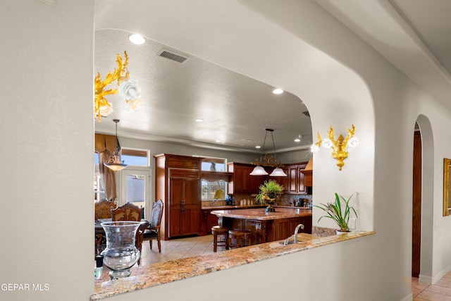 kitchen featuring decorative light fixtures, a center island, kitchen peninsula, and light tile patterned floors