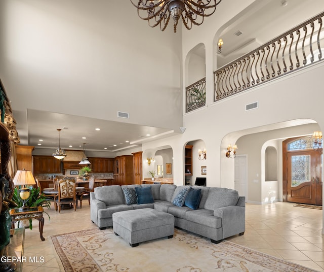 tiled living room featuring a towering ceiling, a notable chandelier, and built in shelves