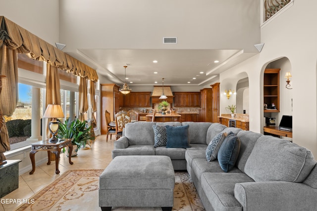 living room with a raised ceiling and light tile patterned flooring