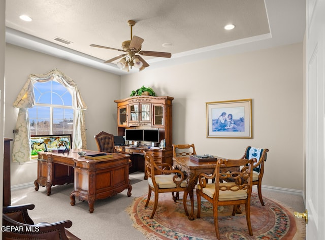 carpeted office with a textured ceiling, a raised ceiling, and ceiling fan