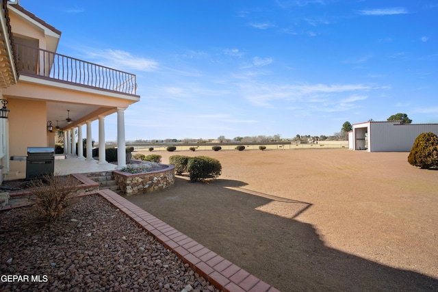 view of yard featuring a balcony, a patio area, and a rural view