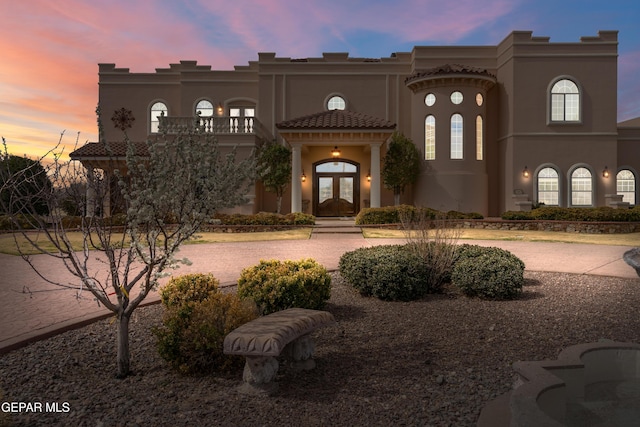 mediterranean / spanish home with french doors, a tile roof, a balcony, and stucco siding