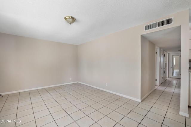 empty room featuring a textured ceiling and light tile patterned floors