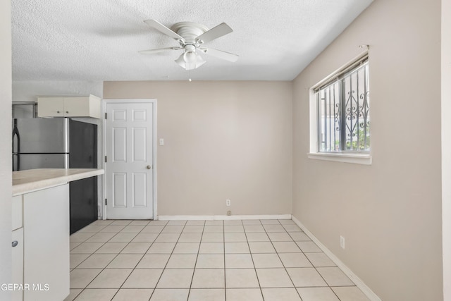 kitchen featuring white cabinetry, a textured ceiling, light tile patterned floors, stainless steel fridge, and ceiling fan