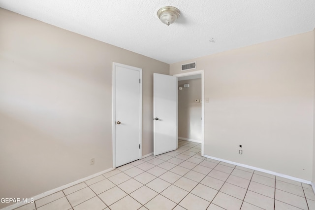 unfurnished bedroom featuring a textured ceiling and light tile patterned floors