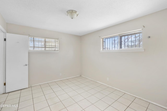 tiled empty room with a healthy amount of sunlight and a textured ceiling