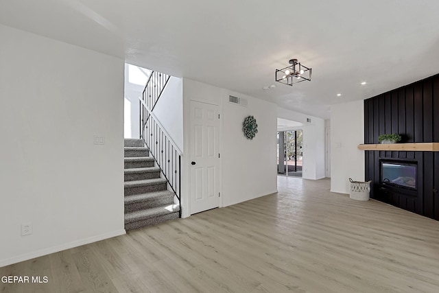 unfurnished living room featuring a fireplace, light hardwood / wood-style floors, and a chandelier