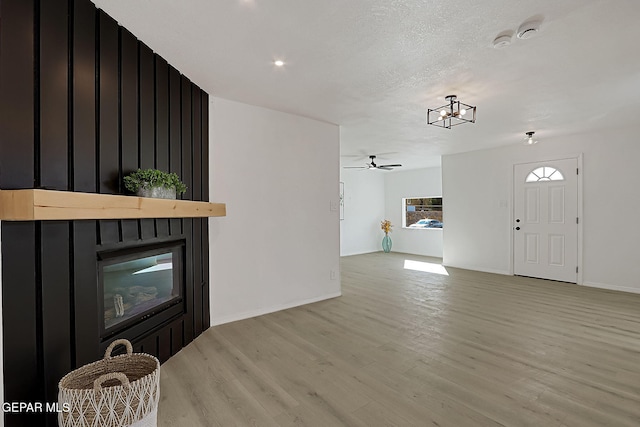 unfurnished living room with ceiling fan, a textured ceiling, and light wood-type flooring