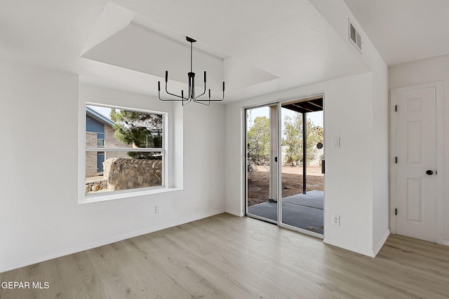 unfurnished dining area with a chandelier, a wealth of natural light, and light hardwood / wood-style floors