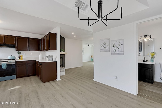 kitchen featuring stainless steel electric stove, decorative light fixtures, ceiling fan, light hardwood / wood-style floors, and dark brown cabinets