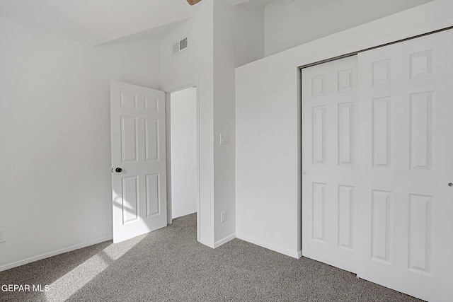 unfurnished bedroom with lofted ceiling, dark carpet, and a closet