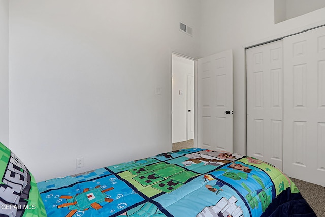 carpeted bedroom with a high ceiling and a closet