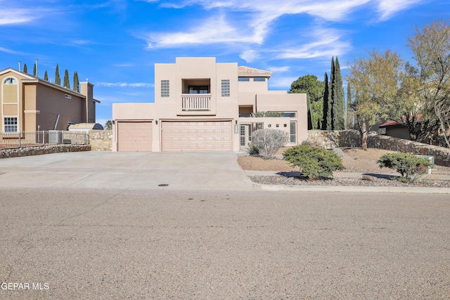 pueblo revival-style home featuring a balcony, a garage, and central air condition unit