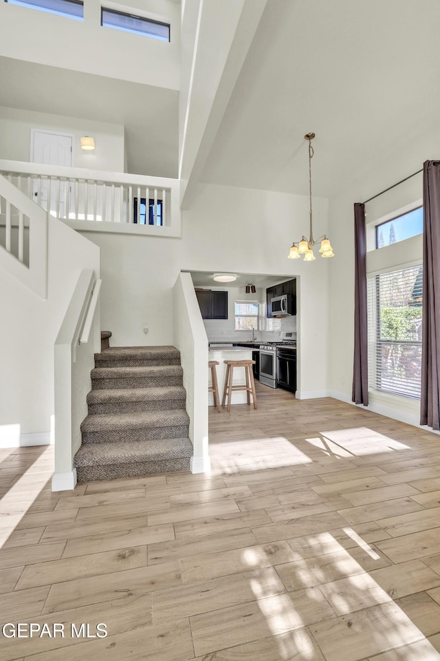 stairway featuring a notable chandelier, hardwood / wood-style flooring, sink, and a high ceiling