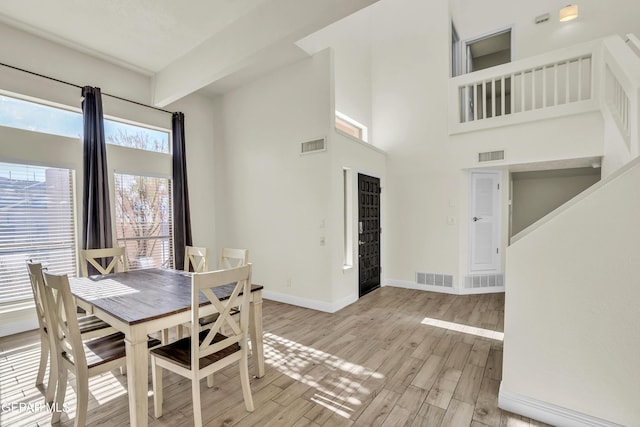 dining area featuring a towering ceiling and light hardwood / wood-style flooring