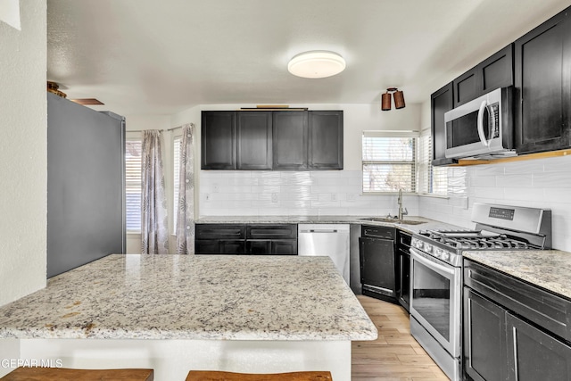 kitchen featuring tasteful backsplash, appliances with stainless steel finishes, light stone countertops, and sink