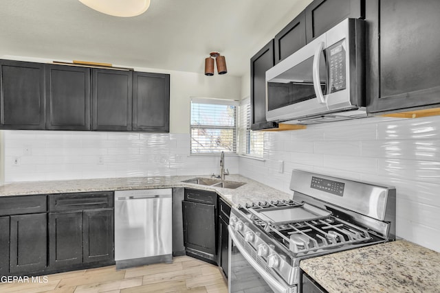 kitchen featuring light stone counters, sink, backsplash, and stainless steel appliances