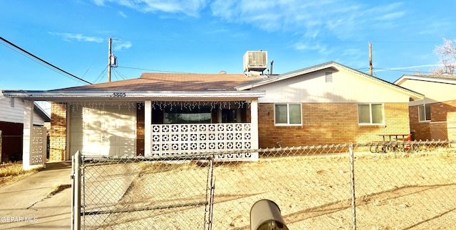 view of side of home with brick siding, cooling unit, a garage, and fence