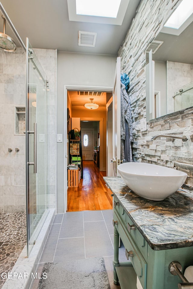 bathroom with vanity, an enclosed shower, tile patterned floors, and a skylight