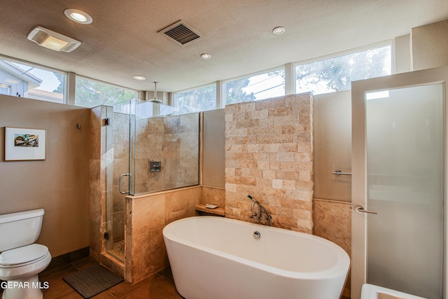 bathroom featuring toilet, separate shower and tub, tile patterned flooring, and a textured ceiling