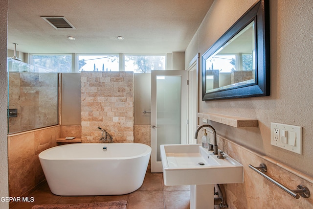 bathroom featuring sink, tile patterned floors, a tub, and a textured ceiling