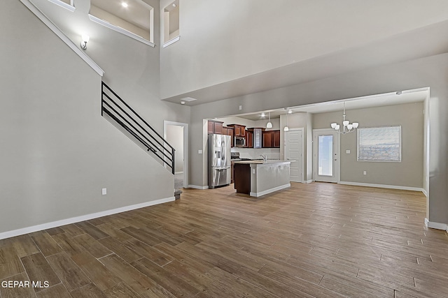 unfurnished living room with an inviting chandelier, a towering ceiling, and sink