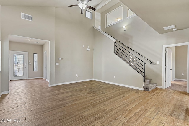 unfurnished living room featuring light hardwood / wood-style floors, ceiling fan, and a high ceiling