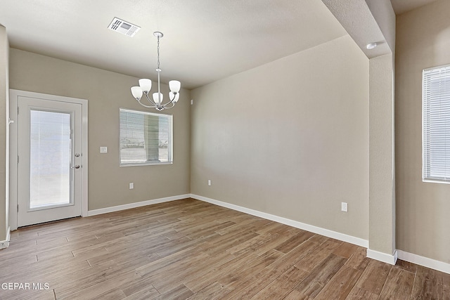 unfurnished dining area featuring light hardwood / wood-style flooring and a notable chandelier