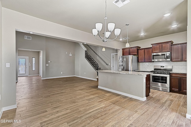 kitchen with a chandelier, hanging light fixtures, light hardwood / wood-style flooring, appliances with stainless steel finishes, and a kitchen island