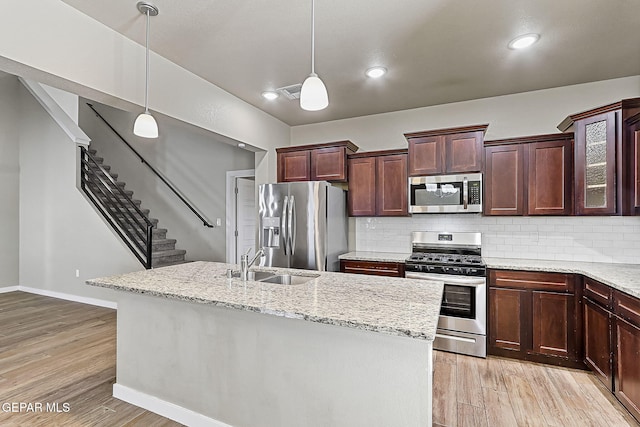 kitchen with pendant lighting, stainless steel appliances, and light wood-type flooring