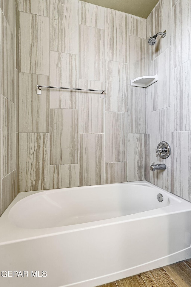 bathroom with tiled shower / bath combo and hardwood / wood-style floors