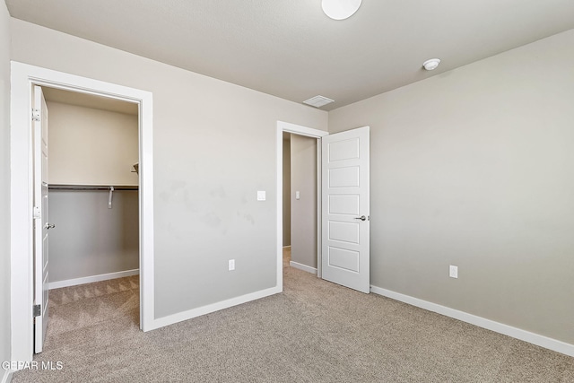 unfurnished bedroom with a walk in closet, carpet floors, and a closet