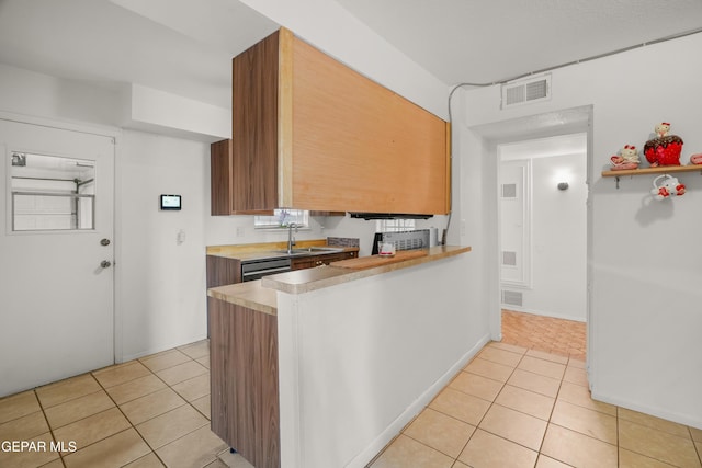 kitchen with light tile patterned flooring, dishwasher, and sink