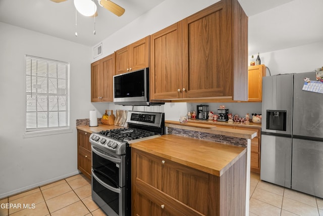 kitchen featuring light tile patterned flooring, ceiling fan, appliances with stainless steel finishes, and wooden counters