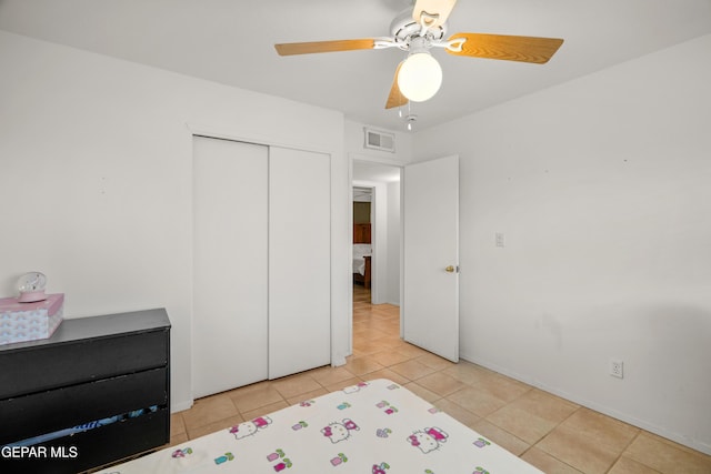 tiled bedroom featuring ceiling fan and a closet