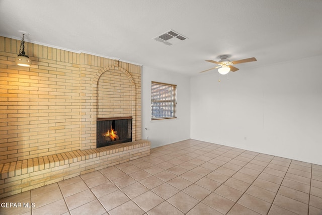 unfurnished living room featuring light tile patterned floors, ceiling fan, a textured ceiling, brick wall, and a brick fireplace