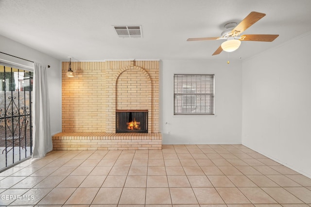 unfurnished living room with a brick fireplace, a healthy amount of sunlight, light tile patterned floors, and ceiling fan