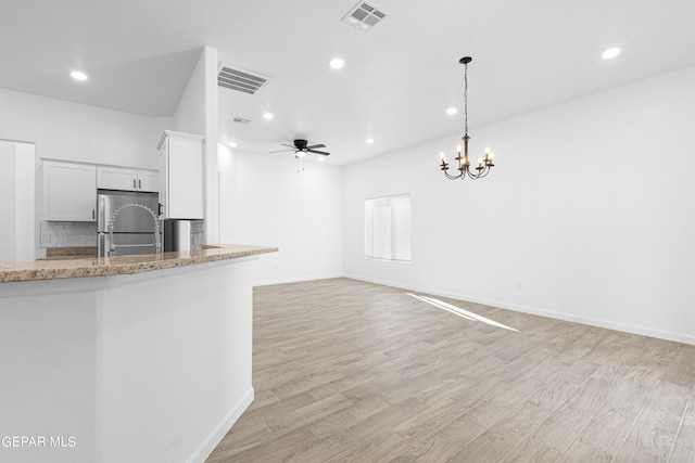 kitchen with pendant lighting, white cabinets, stainless steel refrigerator, and light hardwood / wood-style floors