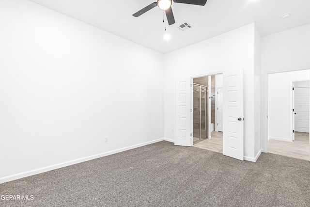 unfurnished bedroom with a high ceiling, connected bathroom, light colored carpet, and ceiling fan