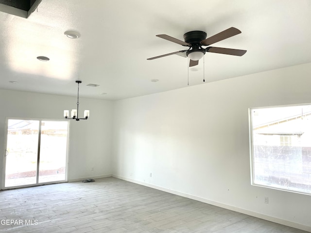 spare room with ceiling fan with notable chandelier and light hardwood / wood-style flooring