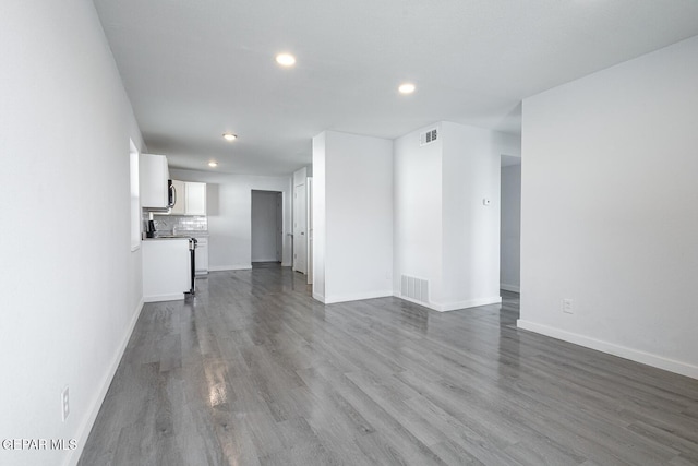 unfurnished living room with dark wood finished floors, visible vents, and baseboards