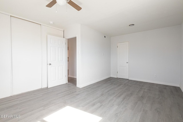 unfurnished bedroom with a ceiling fan, a closet, light wood-style flooring, and baseboards