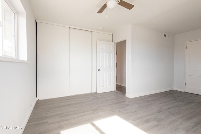 unfurnished bedroom with light wood-style floors, baseboards, and a closet