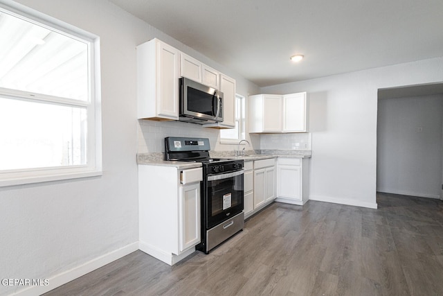 kitchen featuring stainless steel appliances, backsplash, light countertops, and white cabinetry