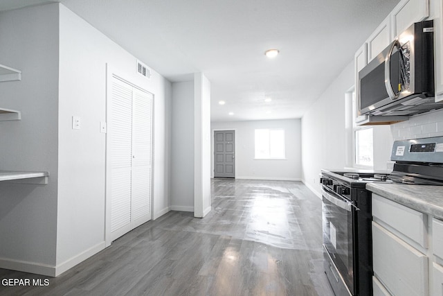 kitchen featuring light wood-style flooring, stainless steel appliances, visible vents, white cabinetry, and baseboards