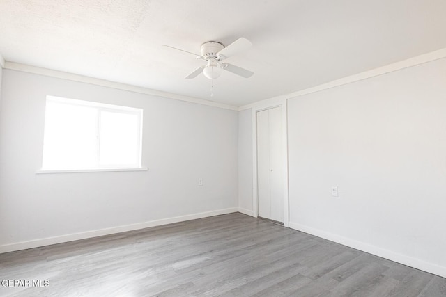 empty room with ceiling fan, baseboards, and wood finished floors