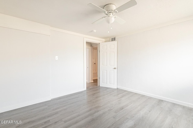 spare room featuring a ceiling fan, visible vents, baseboards, and wood finished floors