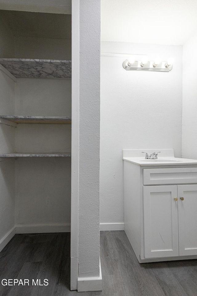 bathroom with baseboards, wood finished floors, and vanity